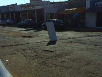 Placa colocada por moradores para sinalizar o buraco da Av Bandeirantes (Foto: Direto das ruas)