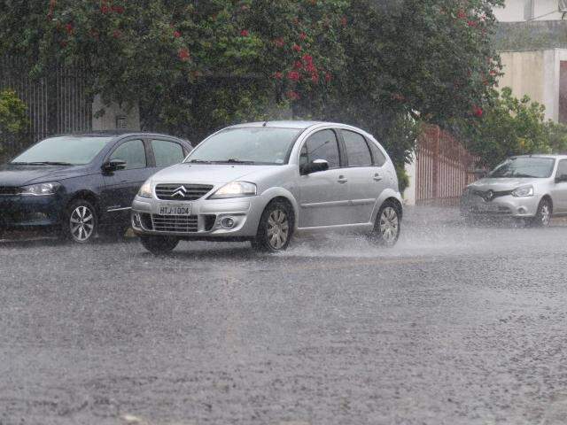 Veículo transitando na região central de Campo Grande evidencia chuva que atinge o local (Foto: Marcos Ermínio)