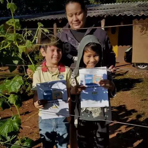 No campo, sorriso de aluno se abre quando vê caderno de atividade