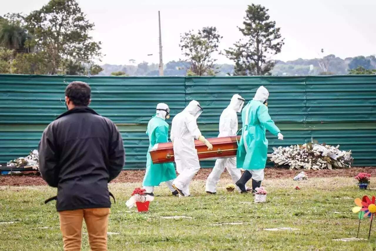 De máscara, homem observa corpo de mulher que morreu pela covid ser enterrado em Campo Grande (Foto: Henrique Kawaminami) -
