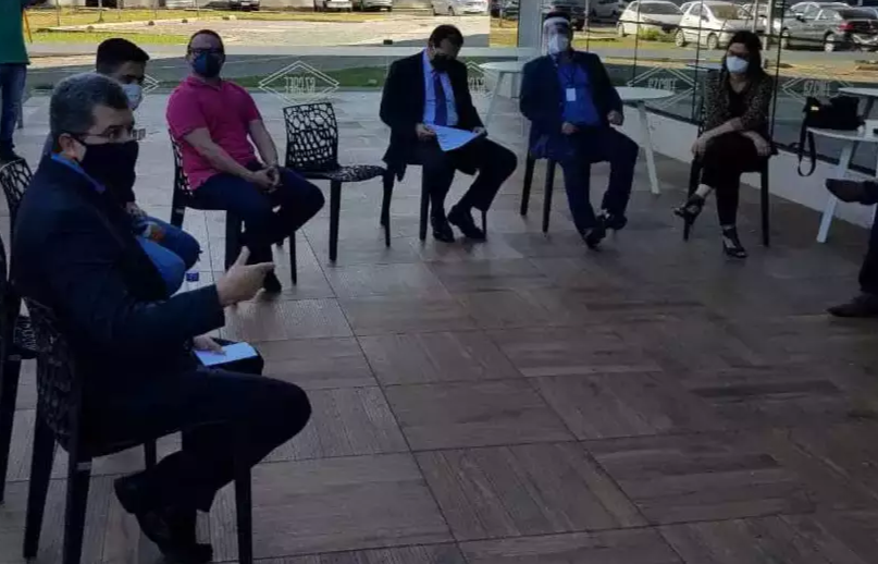 O juiz Ariovaldo Nantes, de terno azul escuro e camisa azul clara, reunido com autoridades de saúde. (Foto: TJMS)