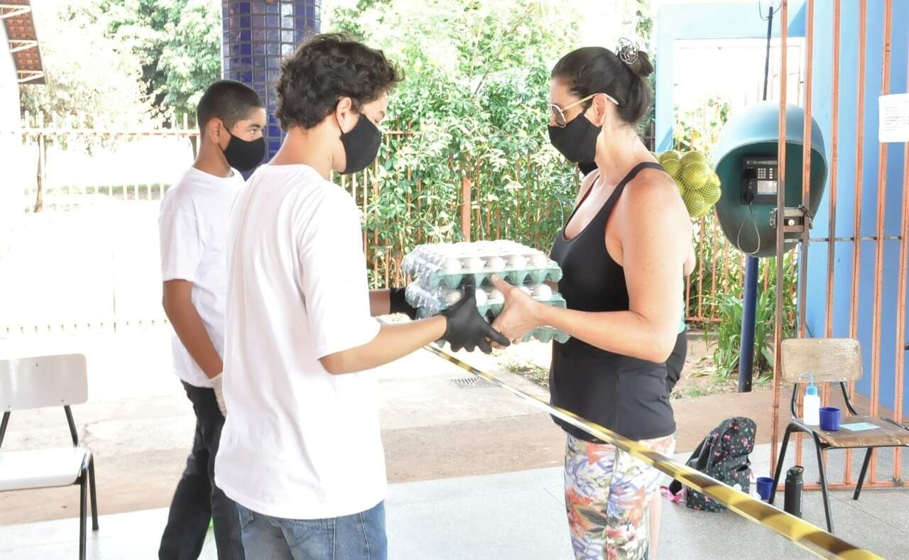 Estudantes recebendo cartelas de ovos que serão entregues para alimentar os animais. (Foto: Divulgação)
