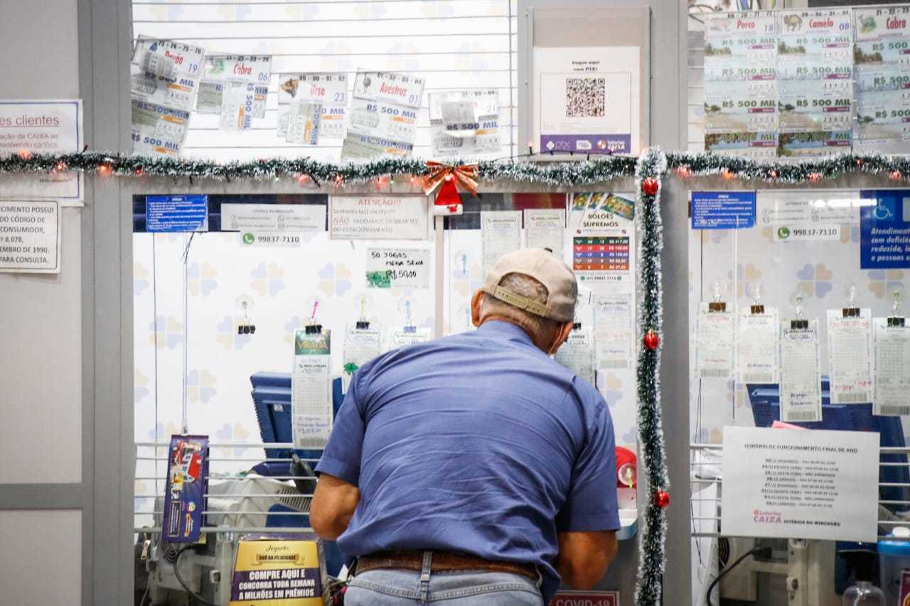 Cliente sendo atendido em lotérica, local onde os beneficiados do auxílio podem receber os pagamentos. (Foto: Henrique Kawaminami) 